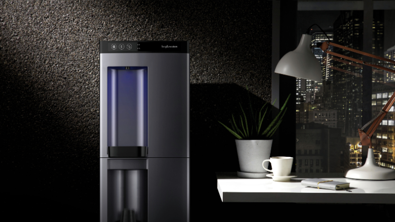 A Borg & Overström B4 countertop water dispenser illuminated by the light of an office desk lamp