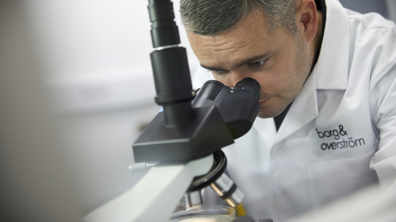 A Borg and Overström scientist analysing microorganisms through a microscope A Borg and Overström scientist analysing microorganisms through a microscope