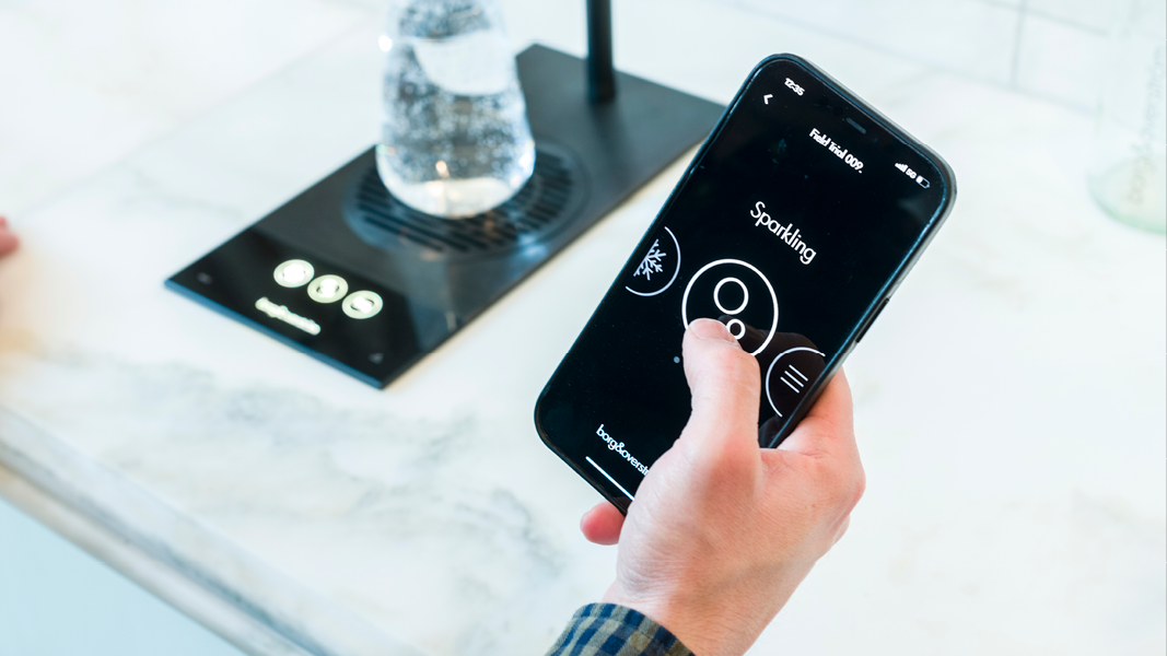 A man using his smart phone to dispense water from a Borg and Overström T2 using the dispensing app.