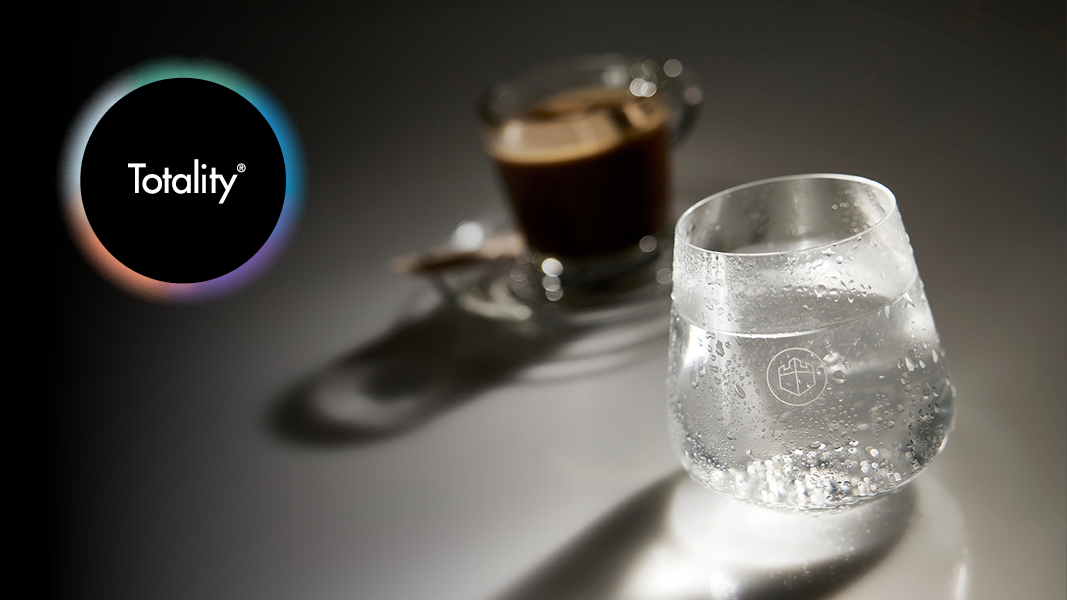 A Totality symbol featuring a clear glass of filtered water in front of a filled coffee mug.