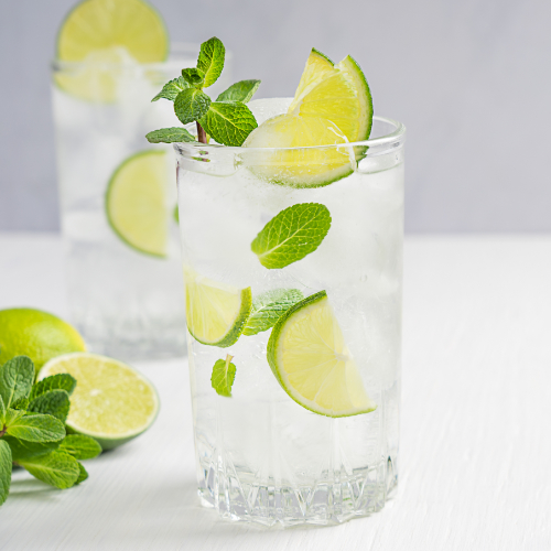 two chilled glass filled with water and slices of lime with an accompanying lime positioned in between.