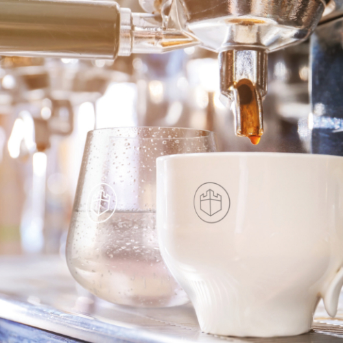 White mug of freshly made coffee standing alongside a clear glass of chilled water