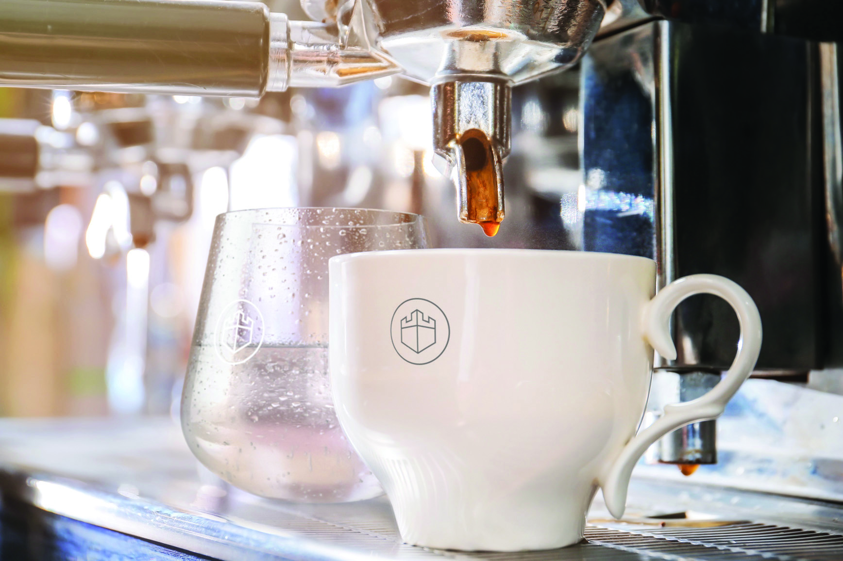 White mug of freshly made coffee standing alongside a clear glass of chilled water