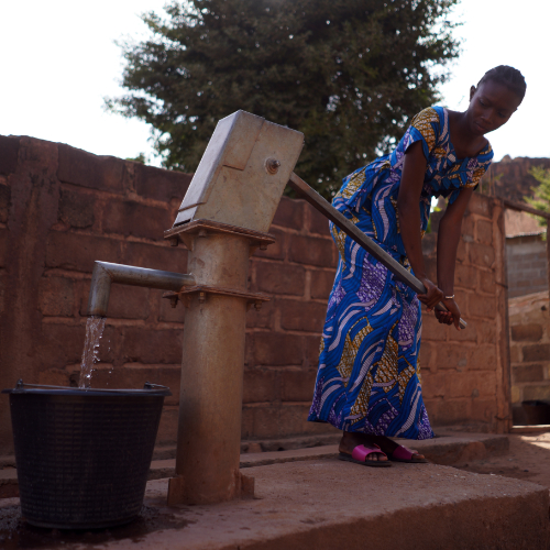 A female using a borehole to dispense water into a bucket