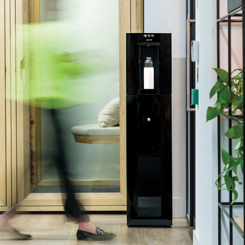 A Borg & Overström floor standing E4, styled 'black',  in an office setting with a water bottle located in the dispense space.