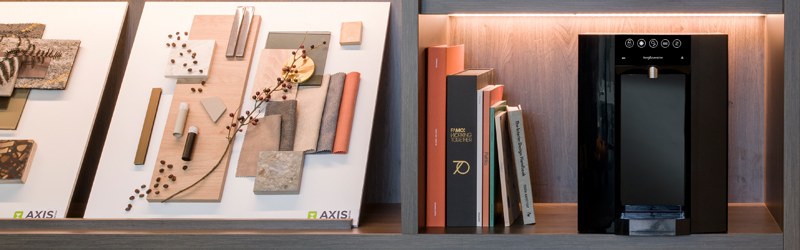 A Borg & Overström B6 located in a luxury environment on a mahogany shelf, accompanied by books and abstract art. 